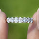 Lab Grown Diamond Oval Seven Stone Wedding Band Held Between Fingers