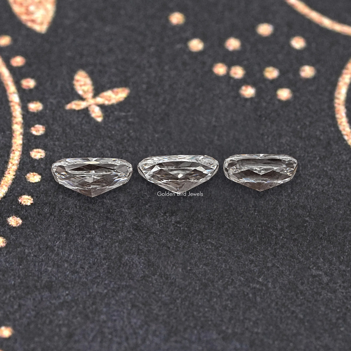 Three elongated cushion-cut loose diamonds, faceted silver-gray