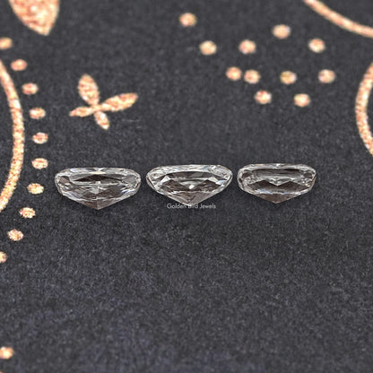 Three elongated cushion-cut loose diamonds, faceted silver-gray