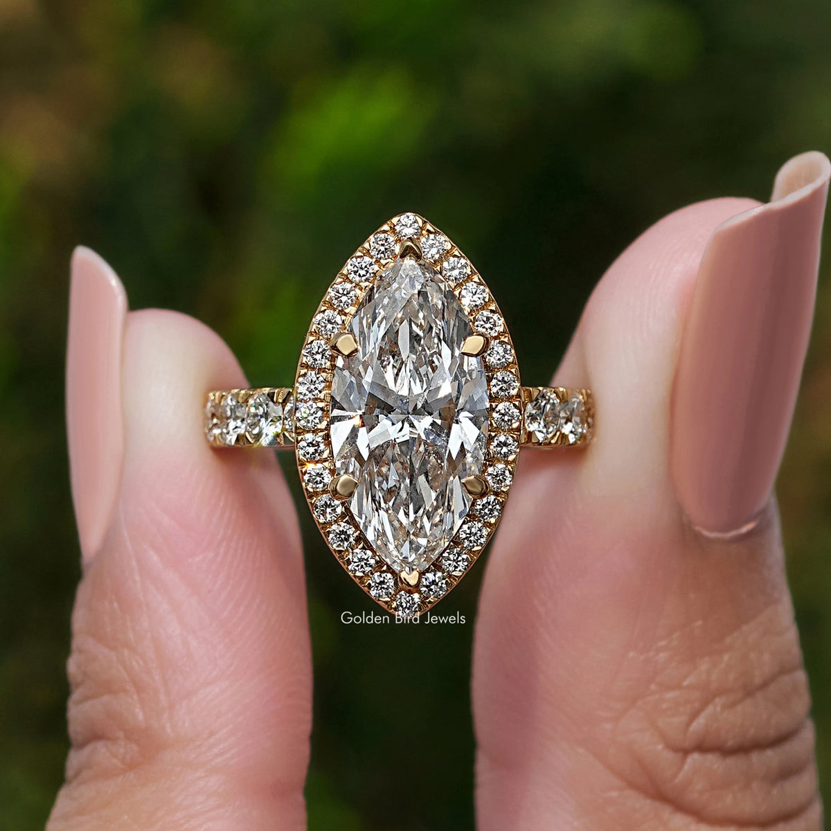 Gold-toned marquise-cut diamond halo engagement ring with glittering side stones