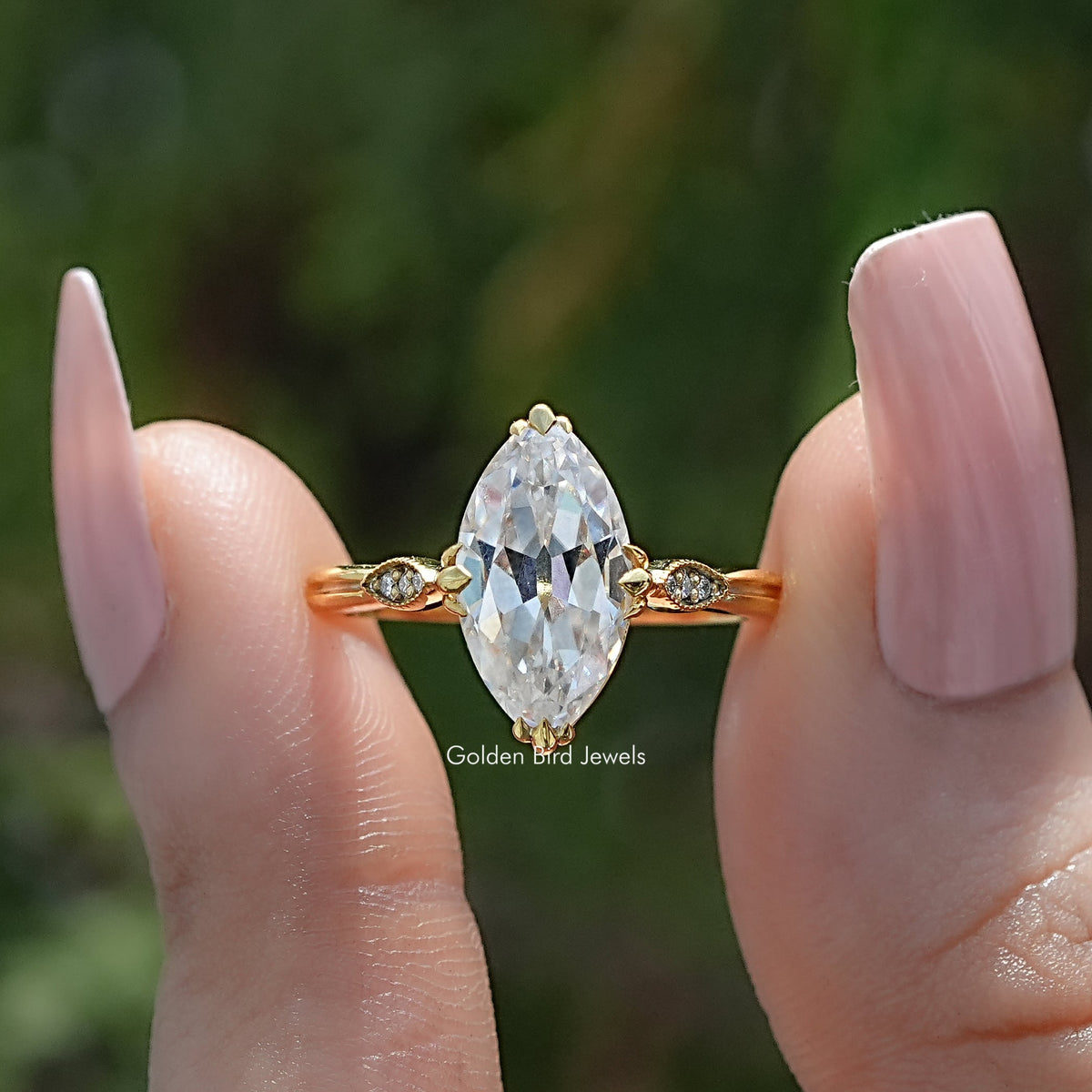 Marquise moissanite solitaire ring with gold-tone band and small side stones, front view