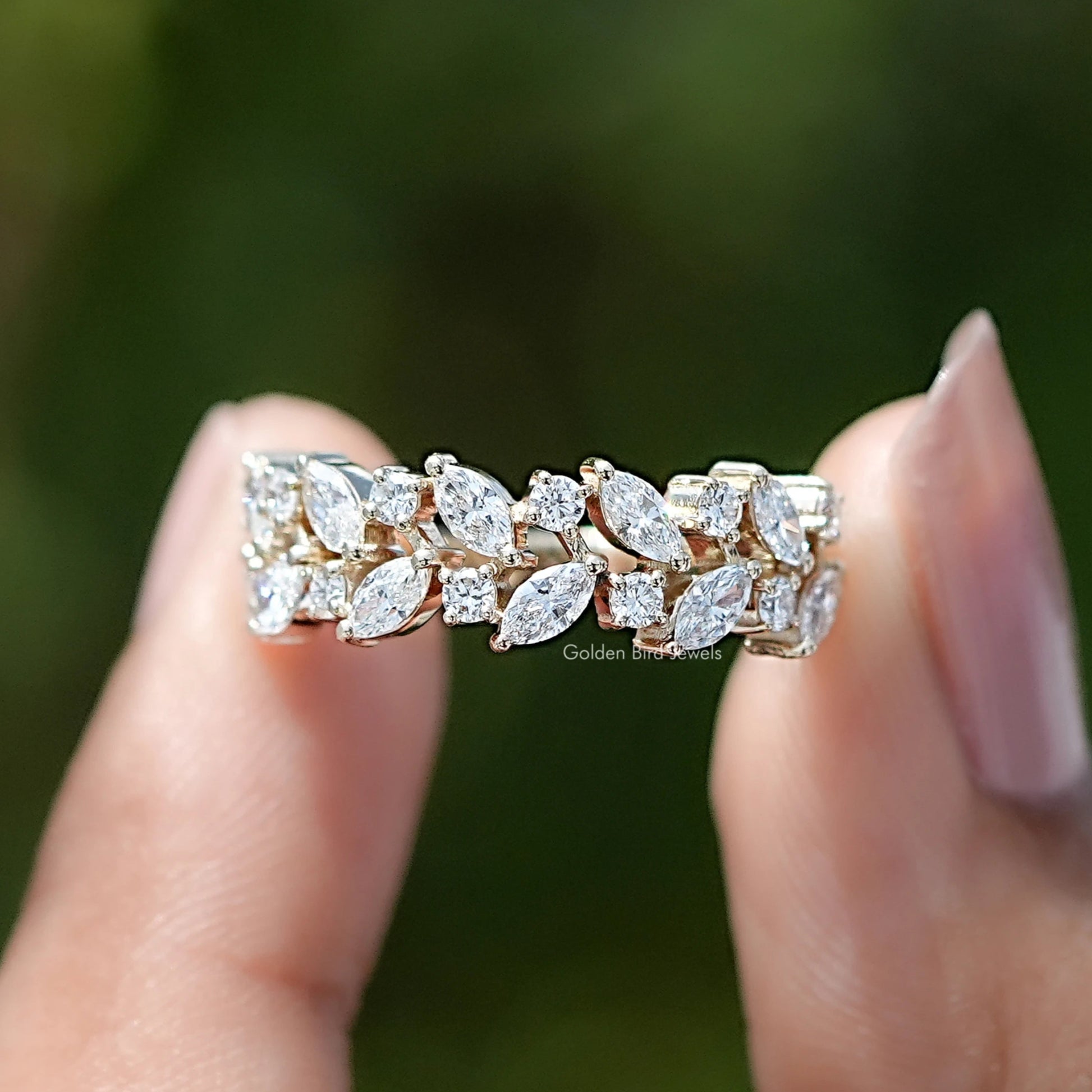 Marquise and Round Cut Lab Diamond Wedding Band Held Between Fingers