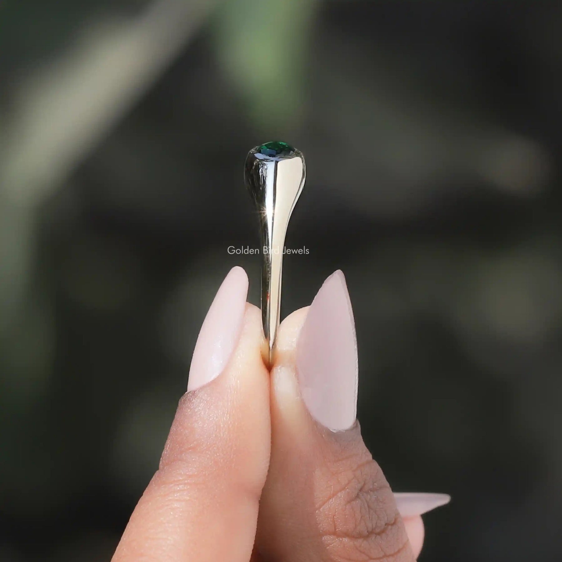 Side View of Bezel Set Marquise Cut Solitaire Engagement Ring In two fingers