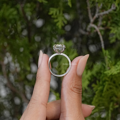 Side view of an emerald-cut moissanite ring showing the raised setting and silver band