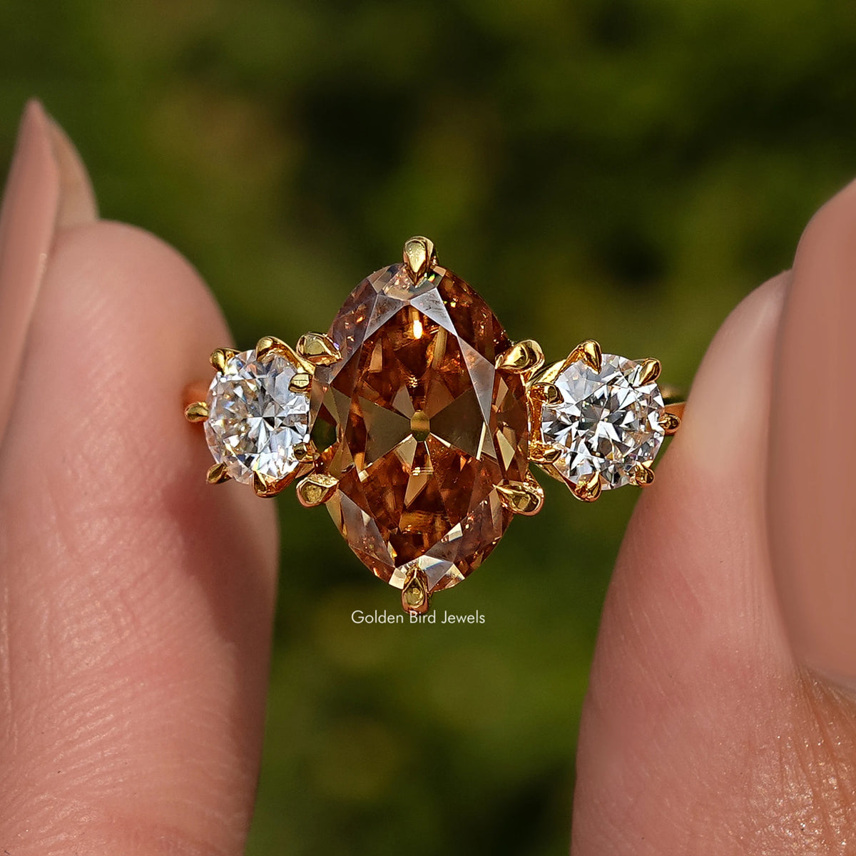 Three-stone ring close-up: large oval center with round side stones in gold-tone
