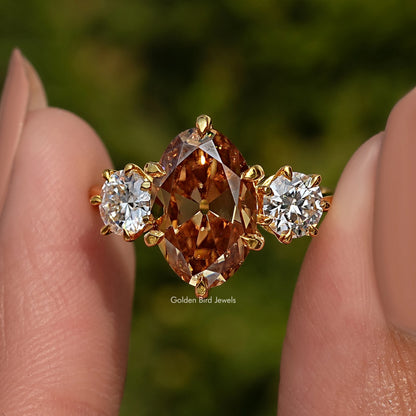Three-stone ring close-up: large oval center with round side stones in gold-tone