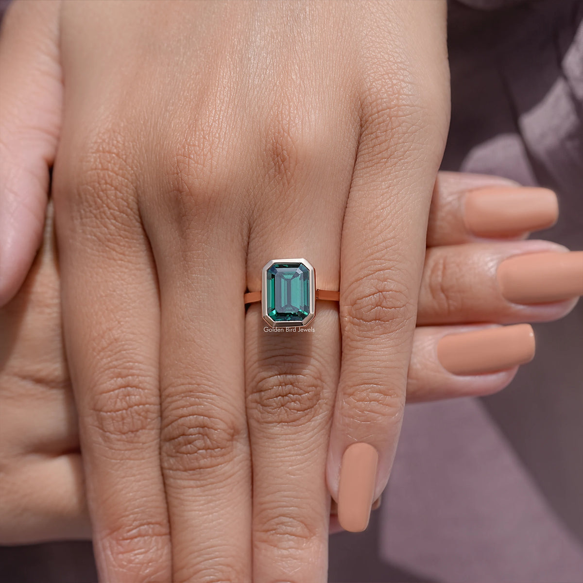 Emerald green moissanite solitaire ring close-up on fingers, rose gold-tone bezel