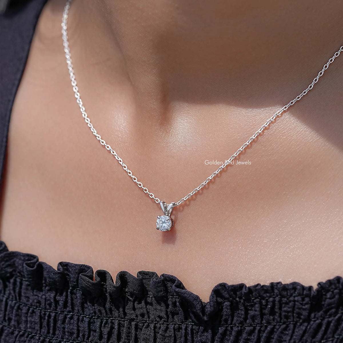 Silver round moissanite pendant necklace resting at the collar over a ruffle top