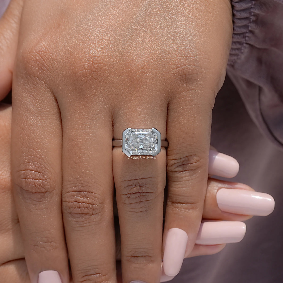 Silver half-bezel solitaire ring with square radiant-cut stone on open hand