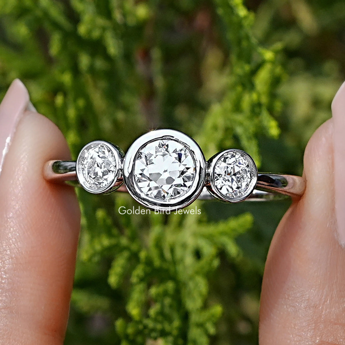 Old European Round Lab Diamond Three Stone Ring Held Between Fingers