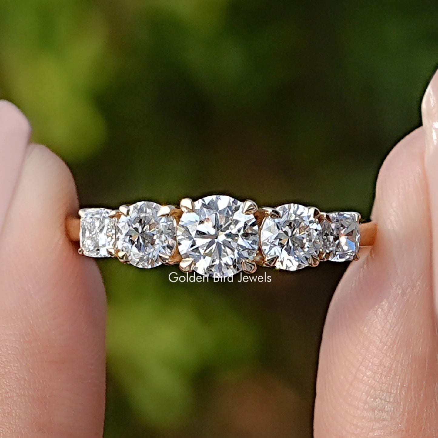 Round Cut Lab Diamond Five Stone Ring Held Between Fingers