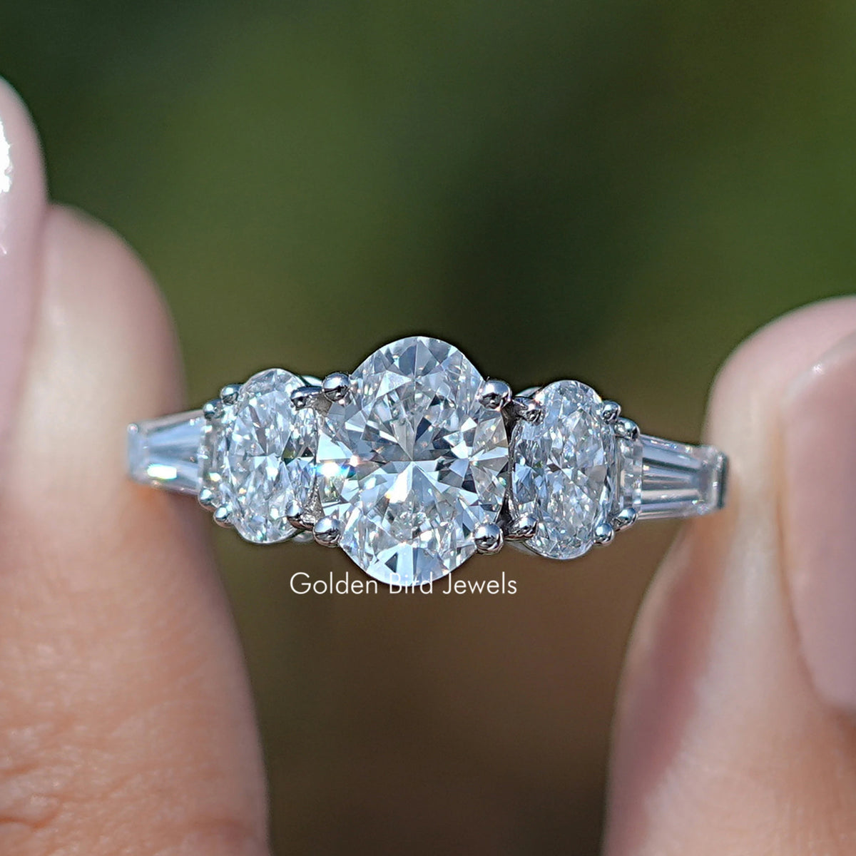 Oval And Tapered Baguette Diamond Five Stone Ring Between Fingers