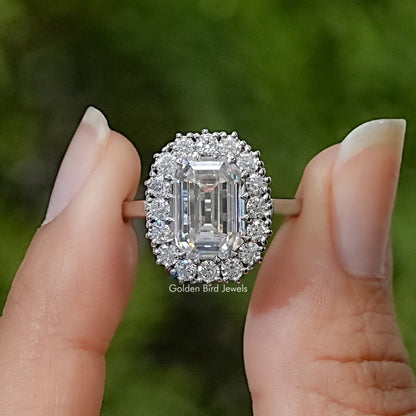Emerald-cut moissanite solitaire ring with a halo of accent stones and a slim silver band