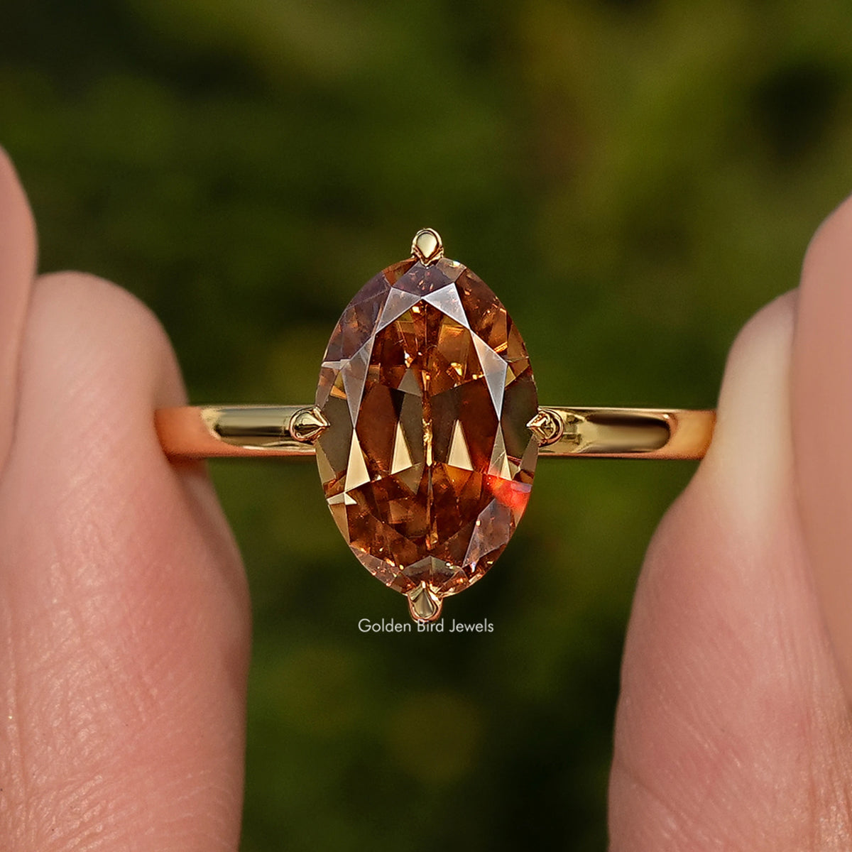 Oval champagne moissanite solitaire ring close-up, gold band with prong details