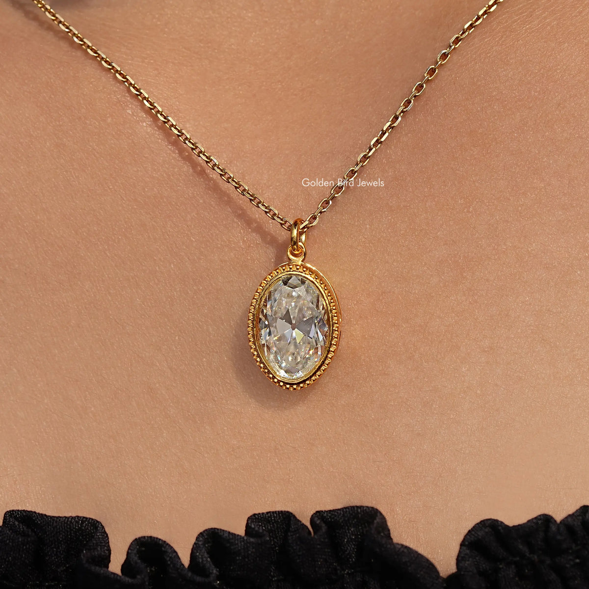 Gold-tone oval bezel pendant with bezel-set white stone hanging on chain