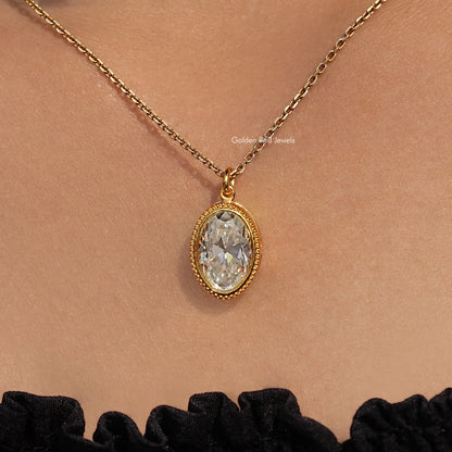 Gold-tone oval bezel pendant with bezel-set white stone hanging on chain