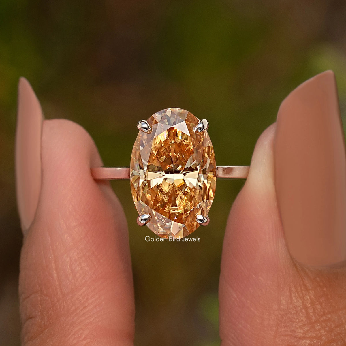 Close-up champagne oval moissanite ring with four prongs on slim band