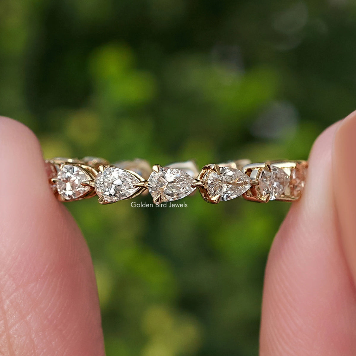 Row of lab-grown diamond pear-shaped stones on eternity band ring