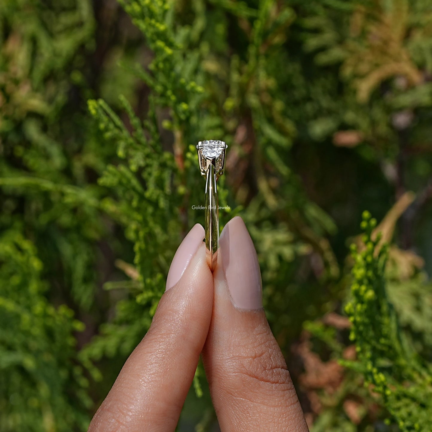 Side View of Pear Cut Lab Diamond Three Stone Engagement Ring In two fingers