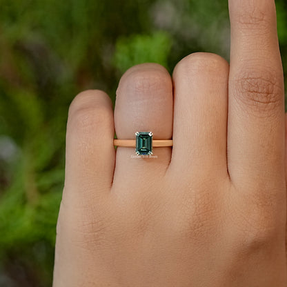 Emerald-cut moissanite ring with dark green center stone on slim band
