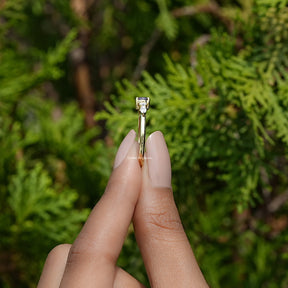 Side View of Round Cut Gemstone Accent Engagement Ring In two fingers