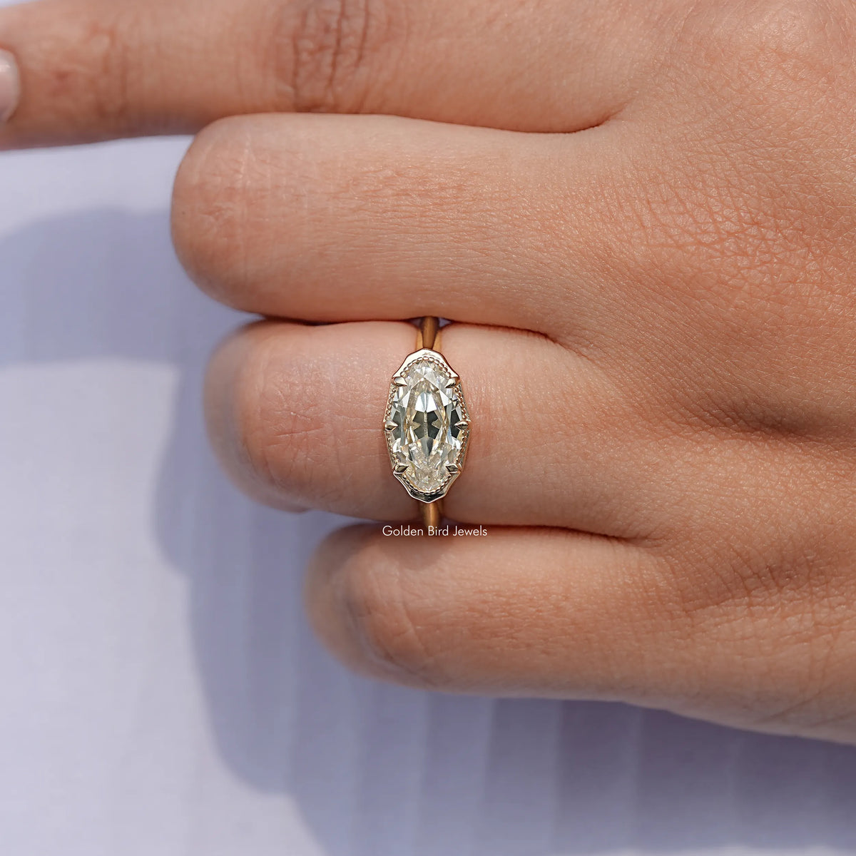 Gold-tone oval solitaire ring with faceted center stone, close-up on hand