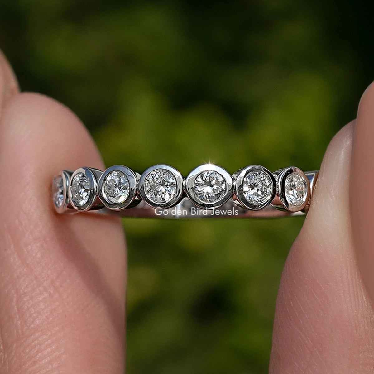 Silver-toned round bezel lab diamond row band, round stones set across the band, close-up