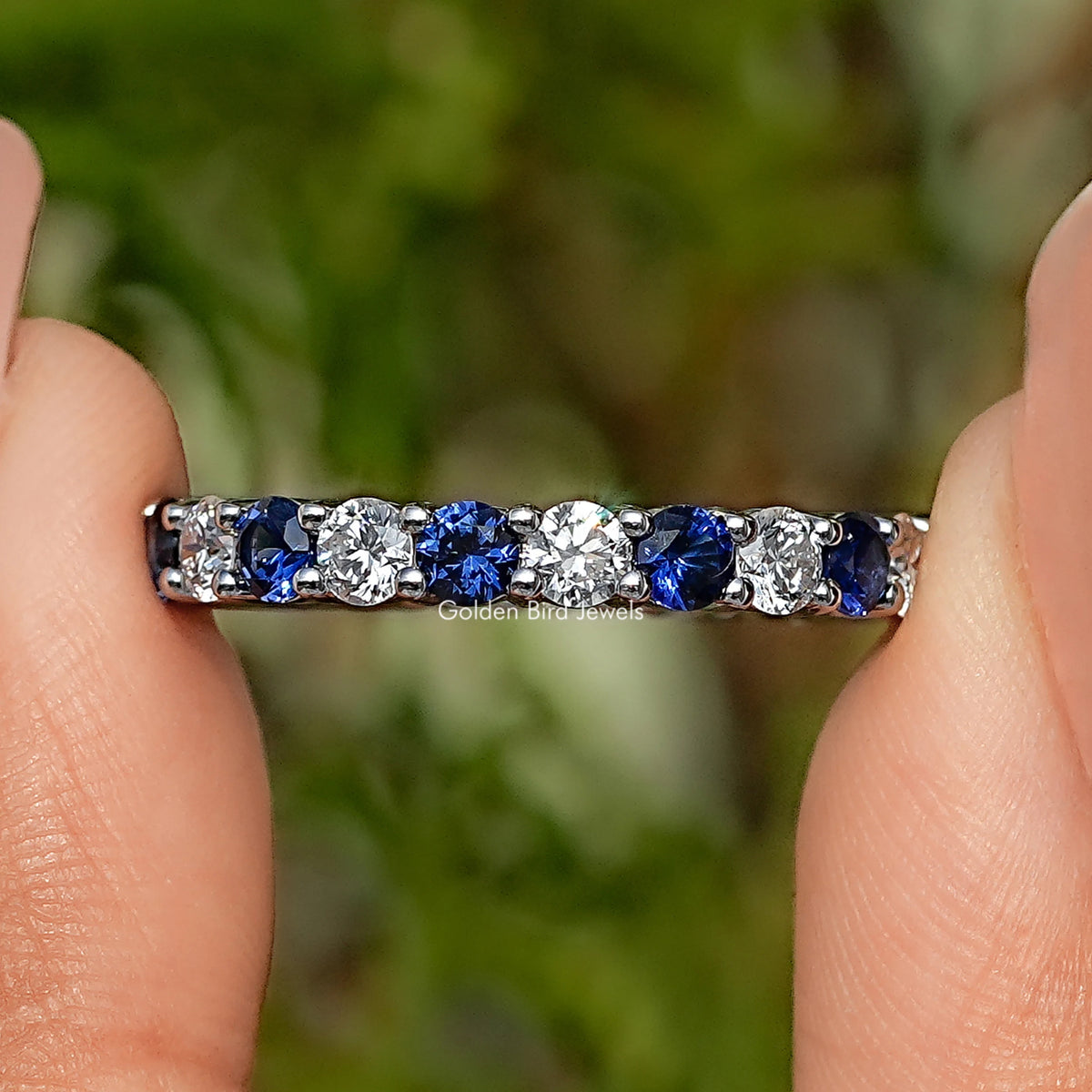 Detailed view of eternity band with alternating blue and clear bezel-set stones