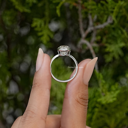 Side view of a sterling silver solitaire ring showing its bezel-set oval moissanite and slim band.