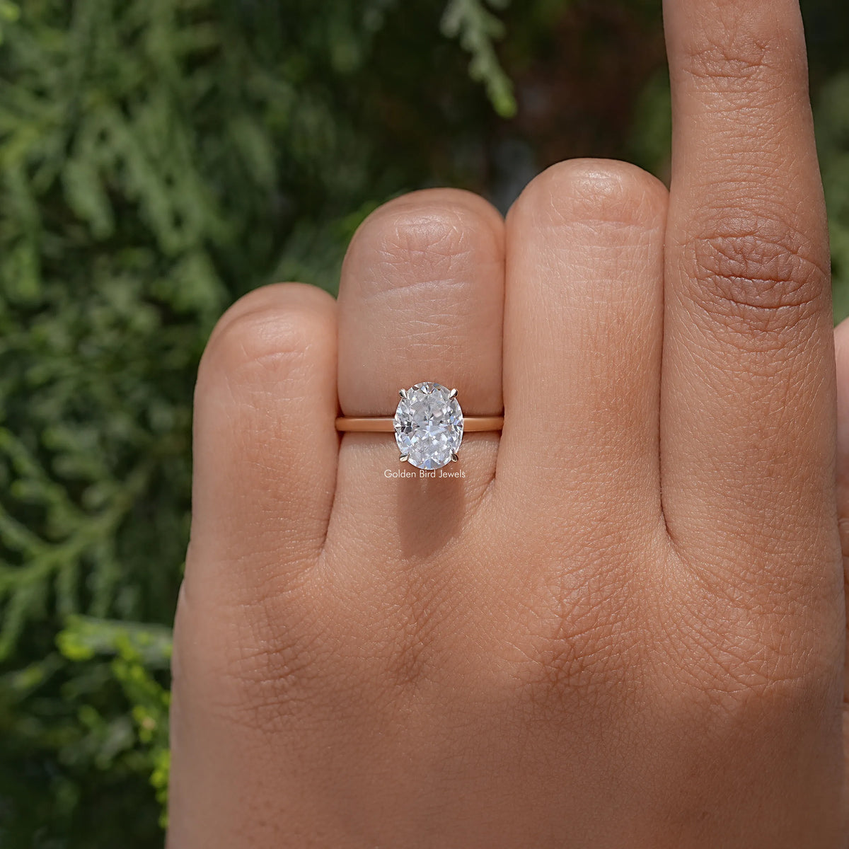 Oval moissanite ring with four-prong setting on hand