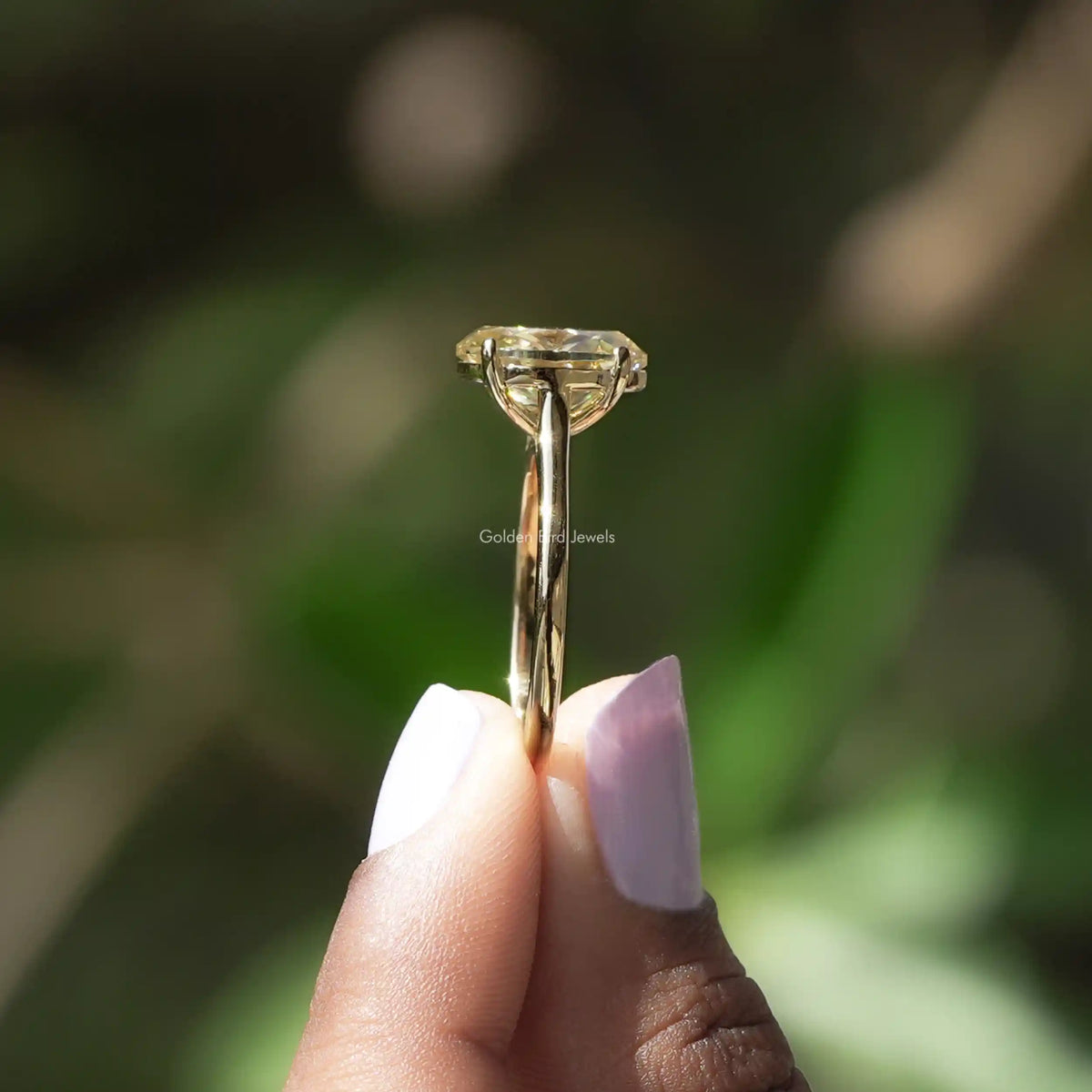 Side View of Oval Cut Solitaire Engagement Ring In two fingers