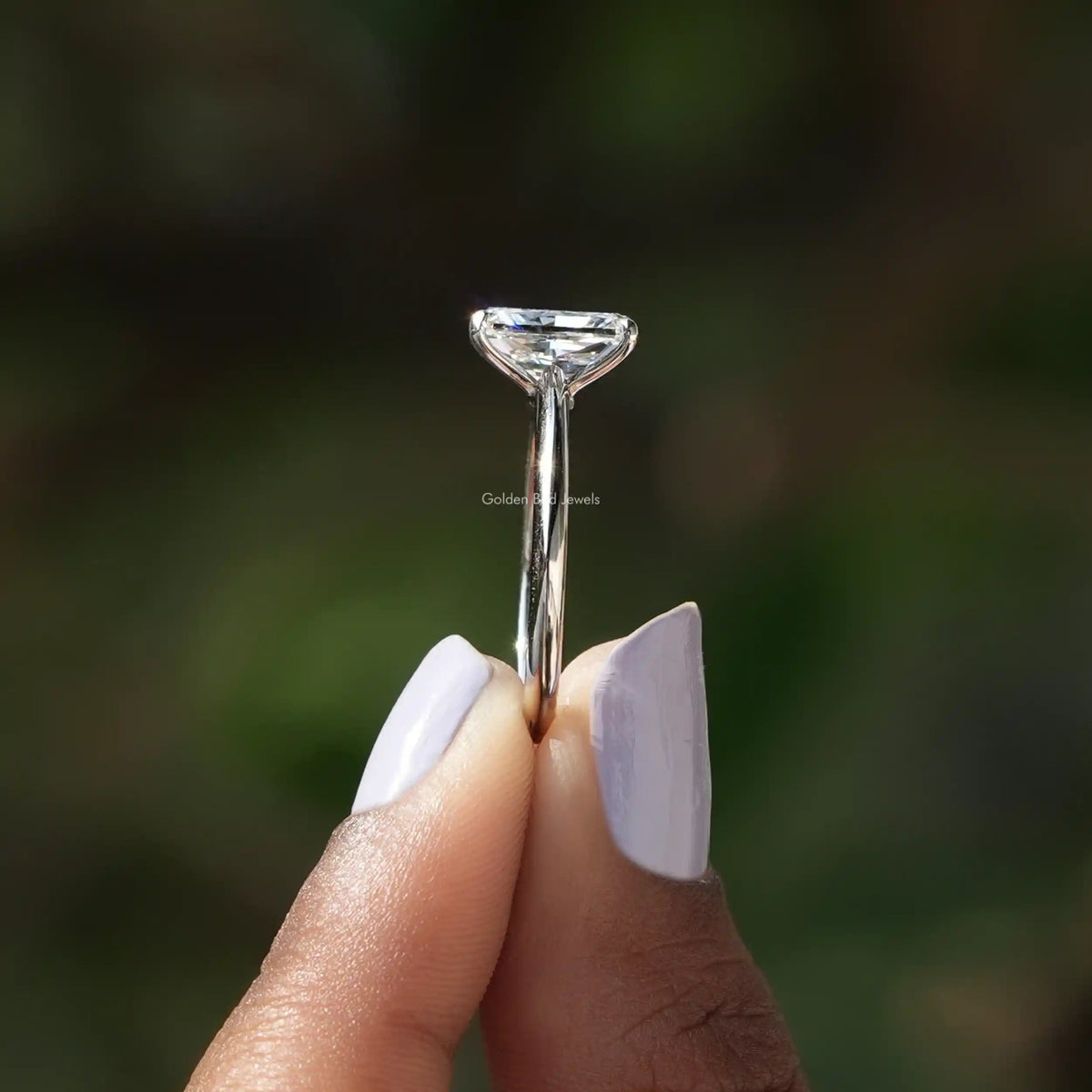 Side View of Radiant Cut Diamond Engagement Ring In two fingers