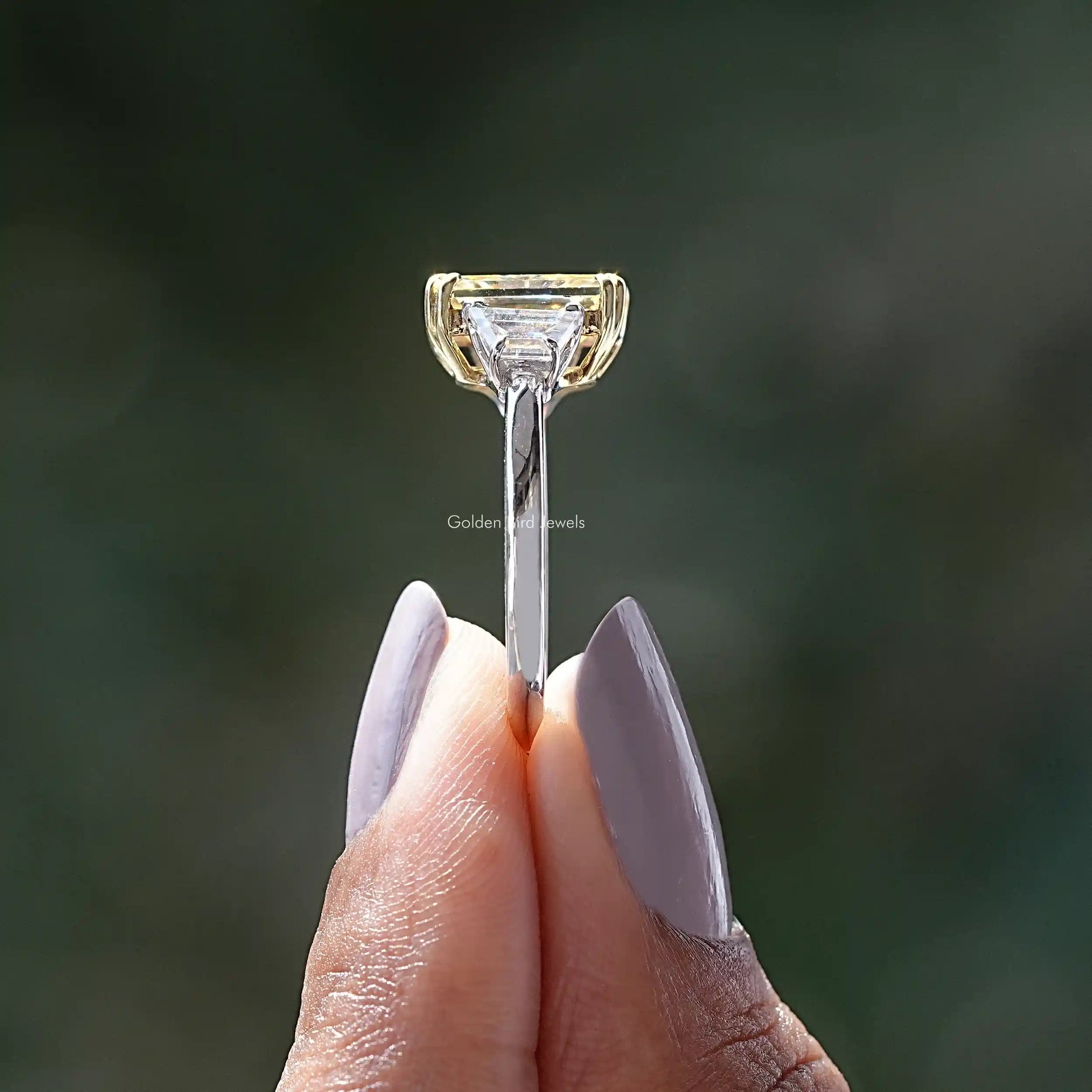 Side View of Radiant And Trapezoid Cut Moissanite Three Stone Ring In two fingers