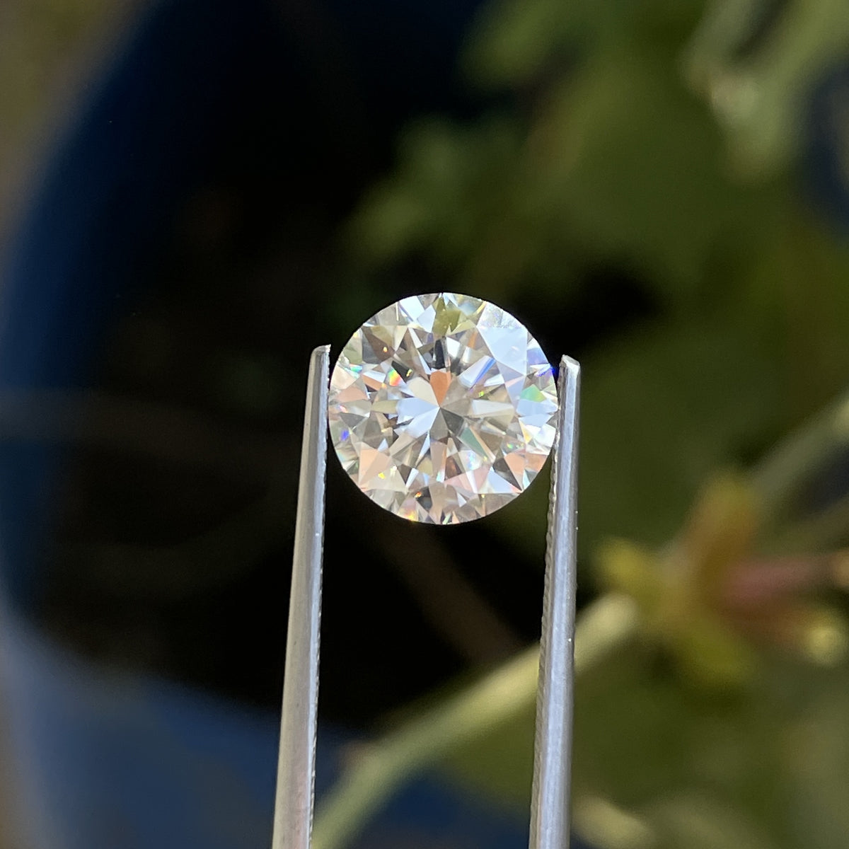 Tweezers holding the Brilliant Cut Round Loose Moissanite 